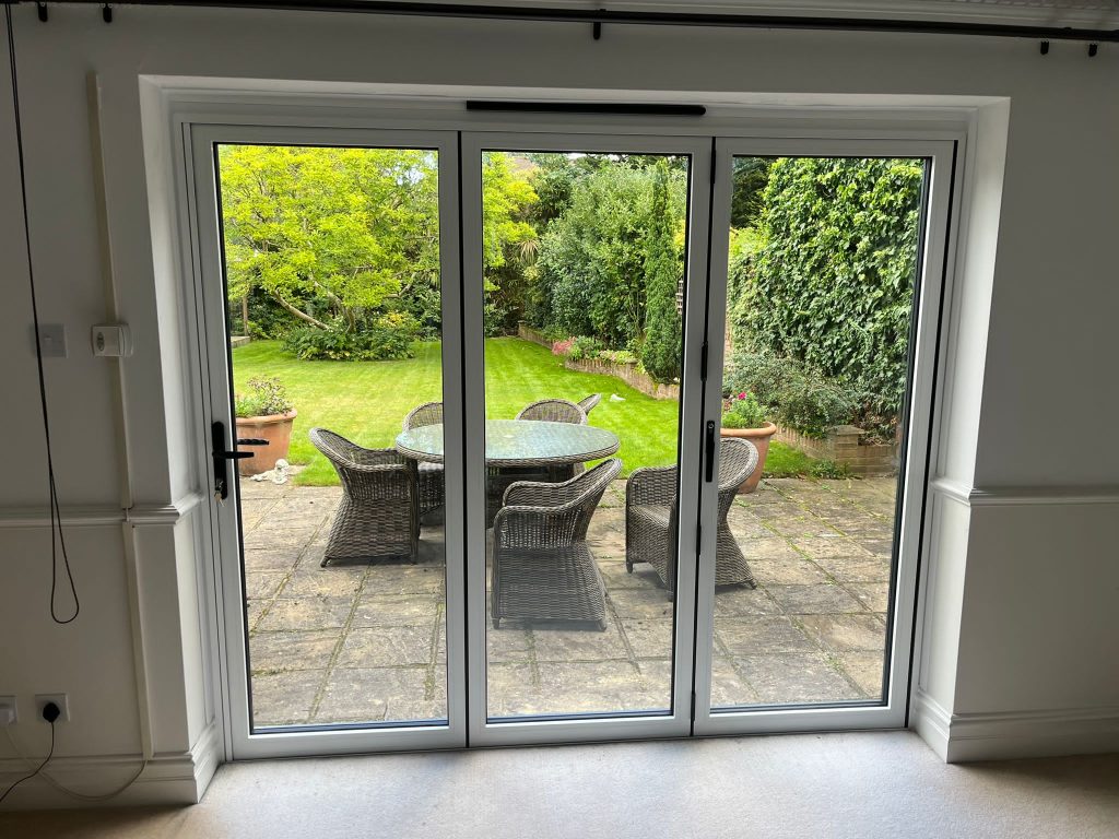 Cortizo bifold doors internal view looking out to garden with rattan furniture